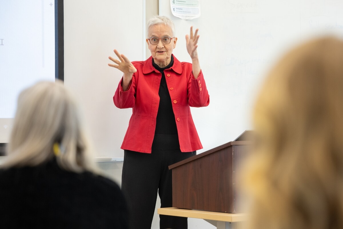 Photo of Jan Taylor in a classroom, lecturing with her hands