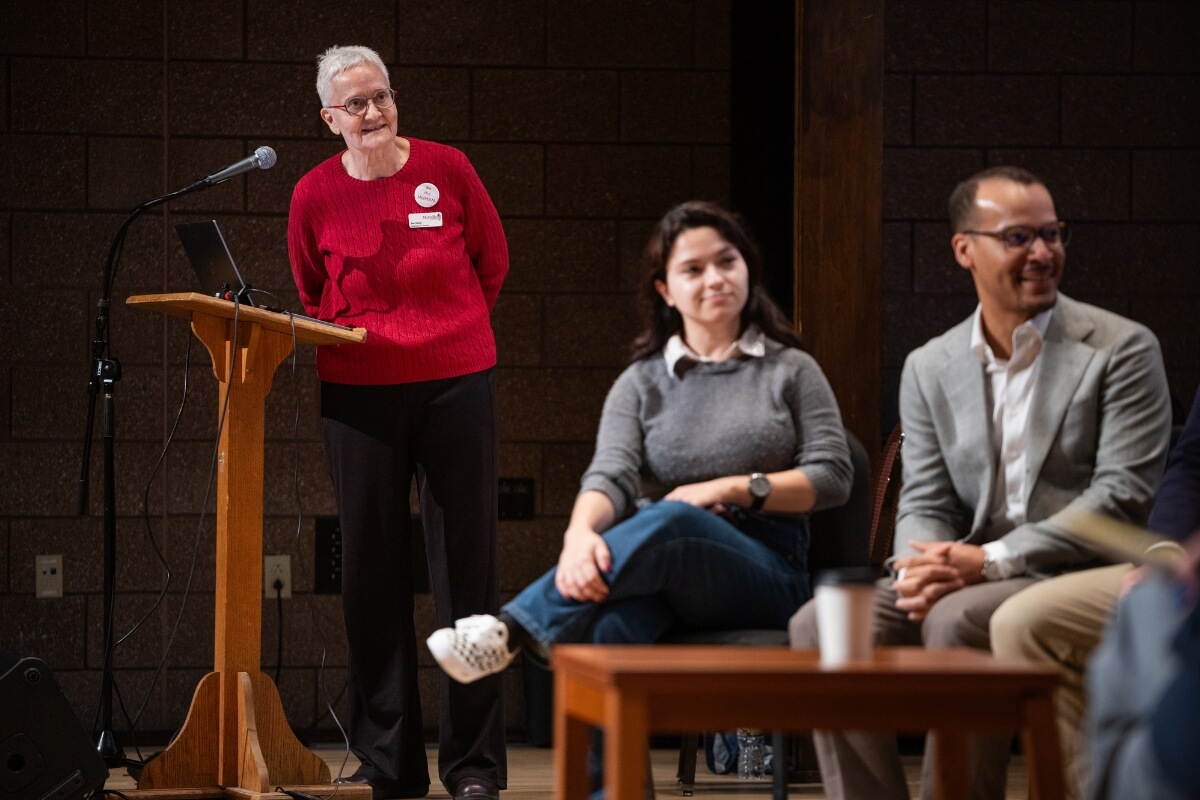 Photo of Jan Taylor looking at two people in the foreground, seated