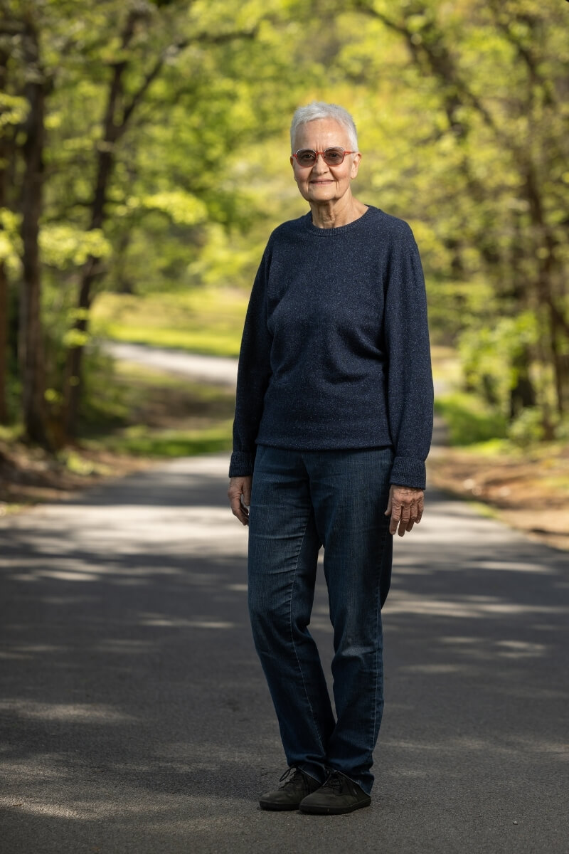 Portrait of Jan Taylor, standing on a path in the Maryville College Woods and smiling