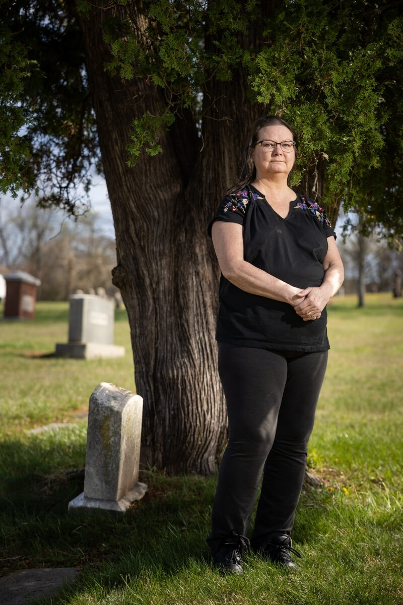 Photo of Nancy Locklin-Sofer standing under a tree in a cemetery
