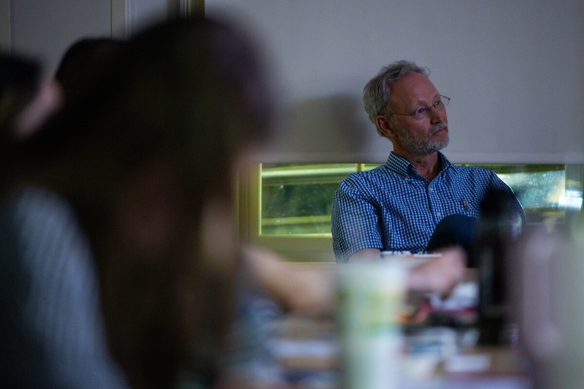 Photo of a man in the dark staring at a screen off camera