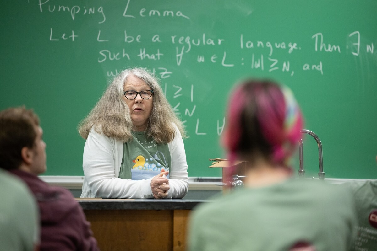 Photo of Dr. Barbara Johnson sitting at a desk at the front of a class