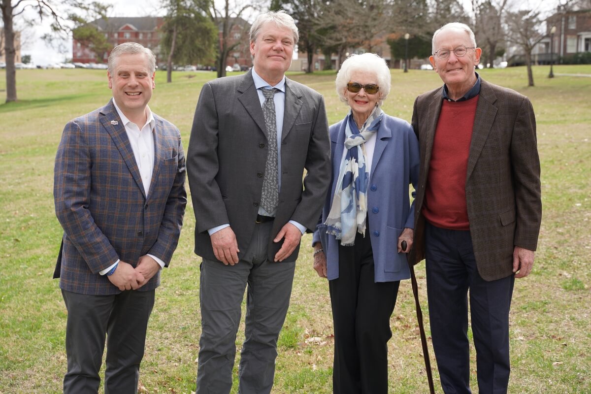 Photo of four people standing on the future site of the Alexander Institute