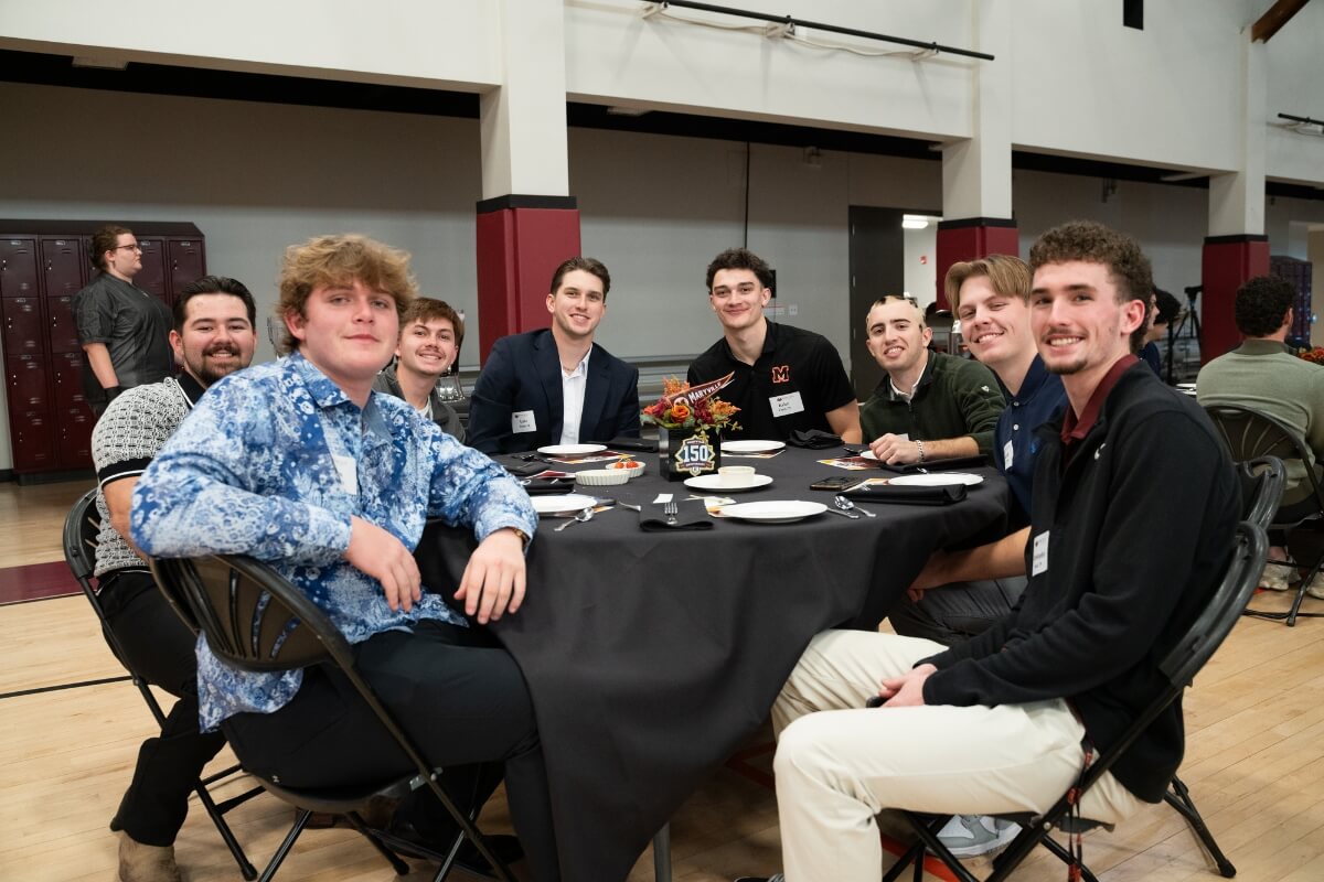 Photo of a group of smiling young men sitting around a table