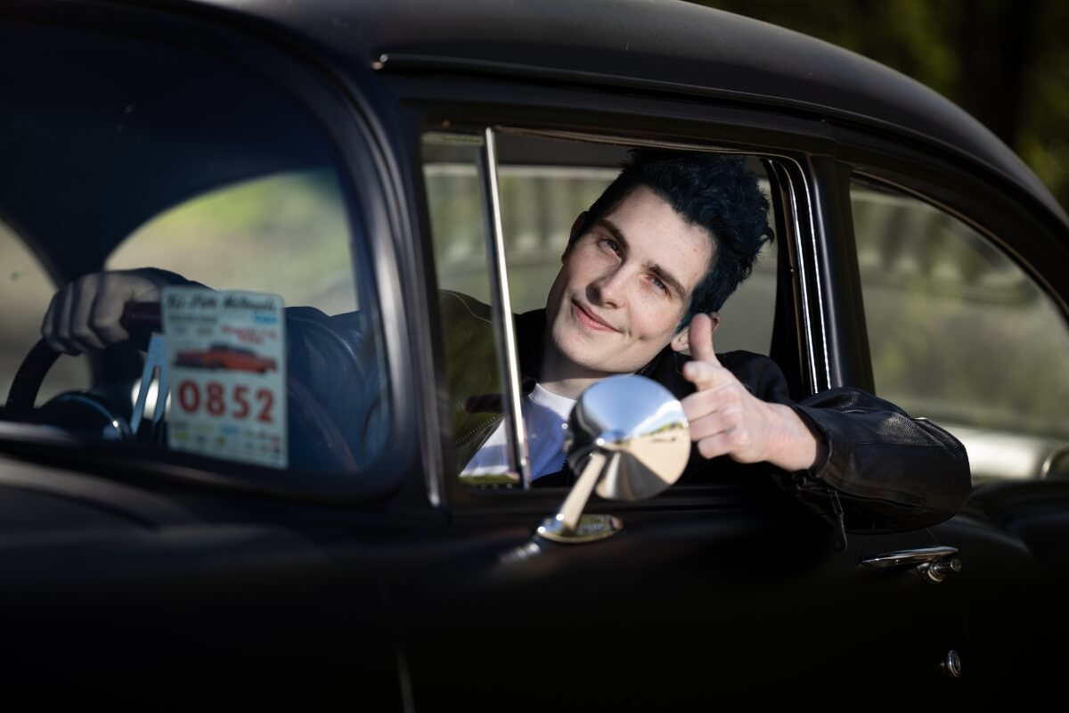 Photo of Maryville College student Ian Bailey behind the wheel of a classic car