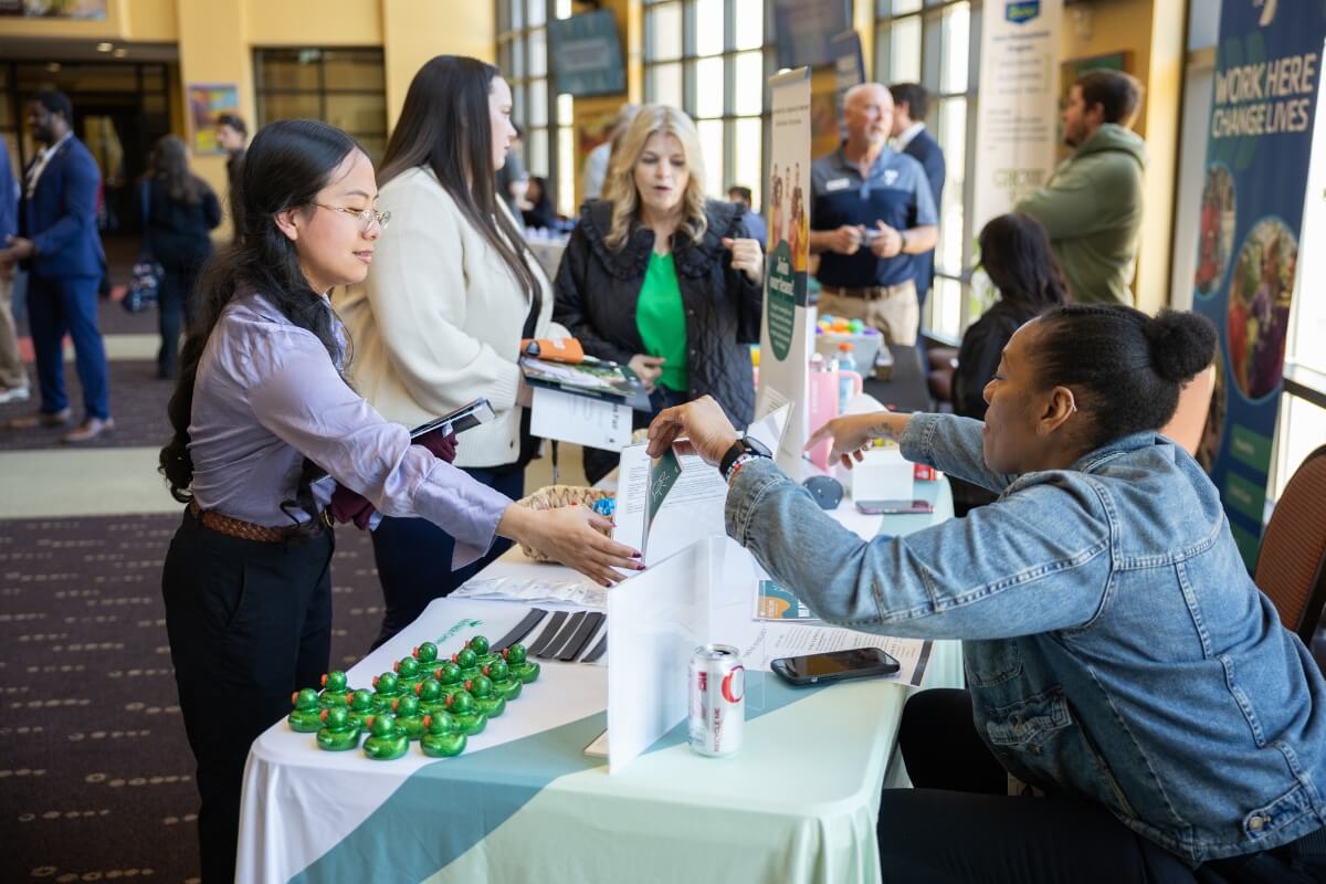 Photo of a student at a career event talking to a seated woman