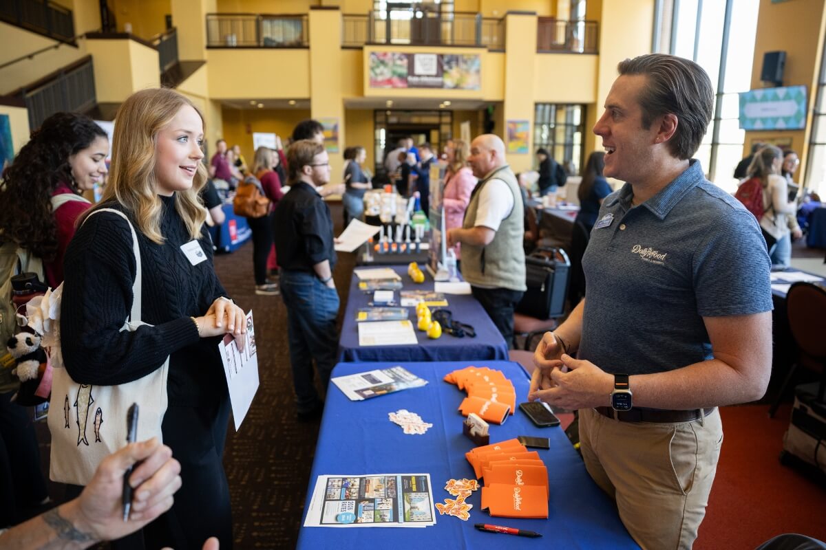 Photo of a student taking to a man at a crowded event