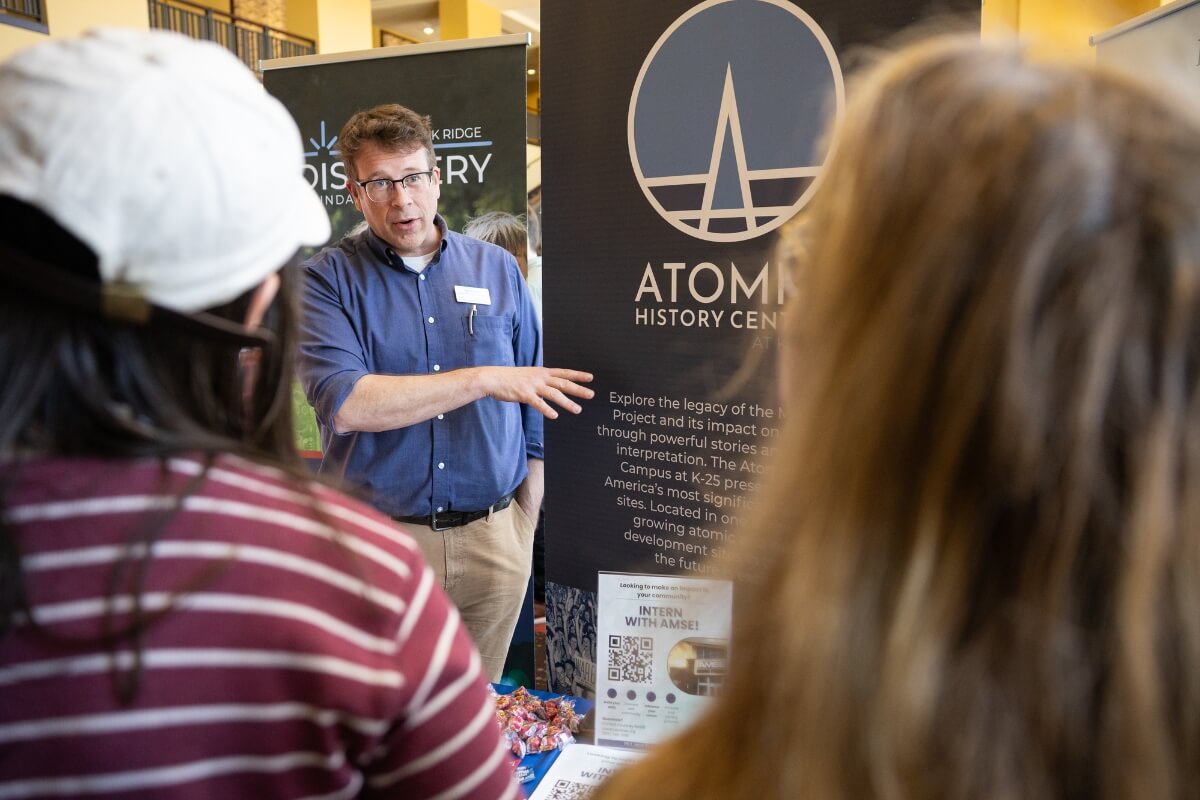 Photo of a man talking to two students, their backs to the camera