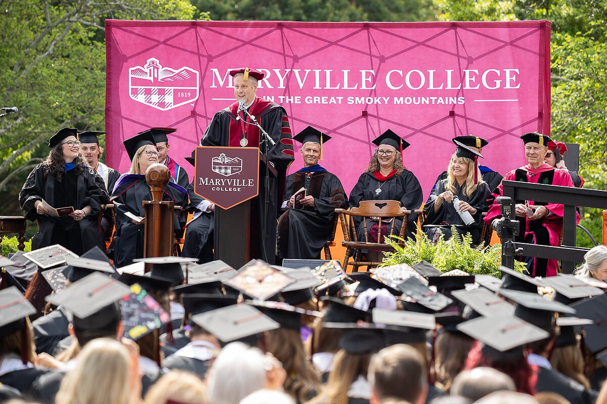 Photo of a man in full graduation regalia welcoming an audience to Maryville College graduation 2026