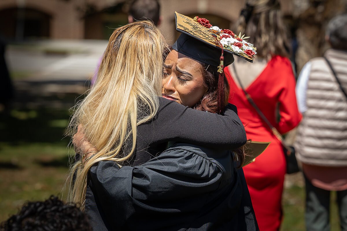 Photo of a woman hugging an emotional graduate