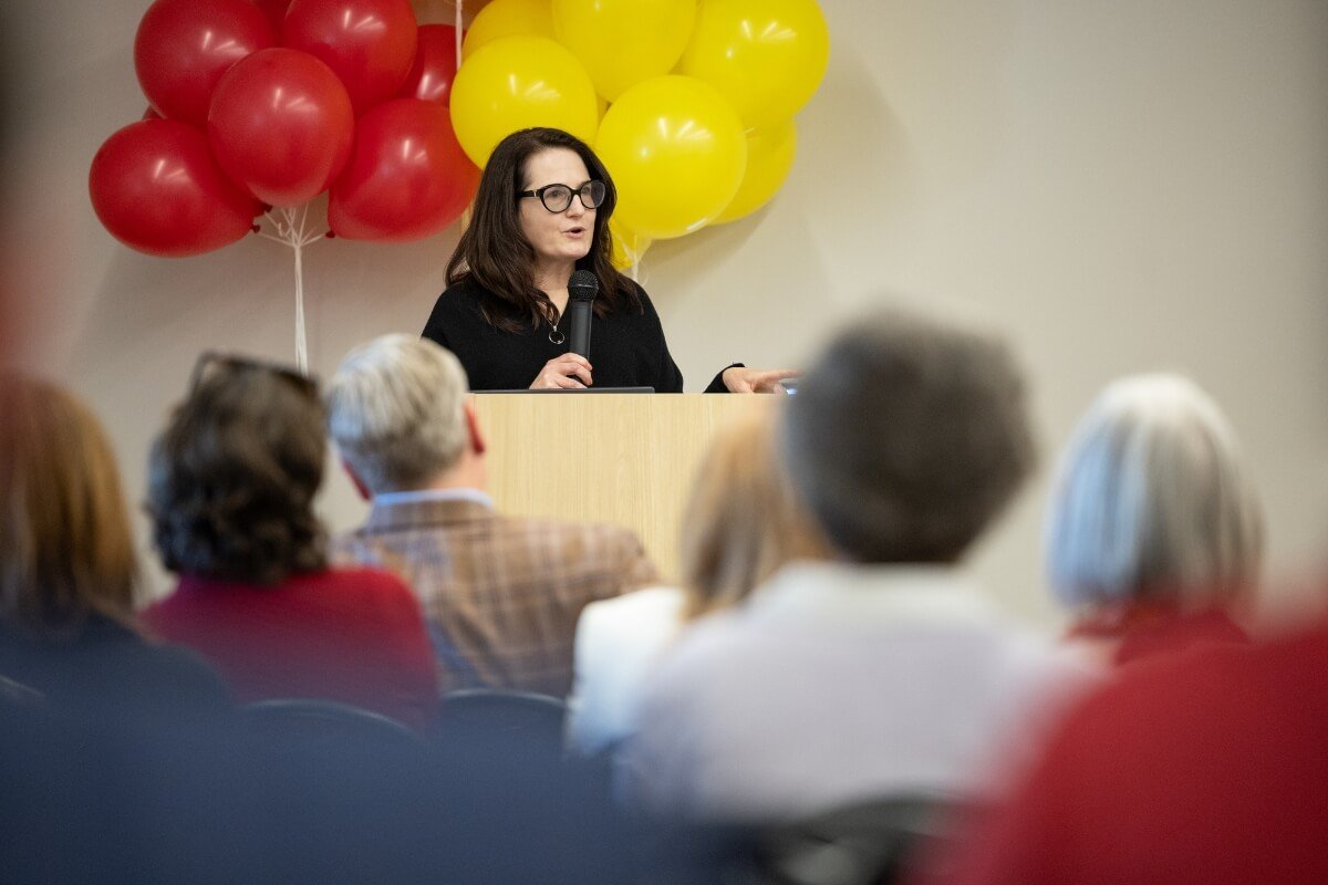 Photo of a woman wearing black and talking to an audience