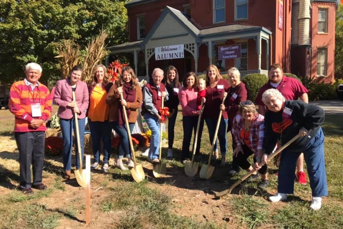 Photo of a large group of Maryville College alums standing around a tree planting