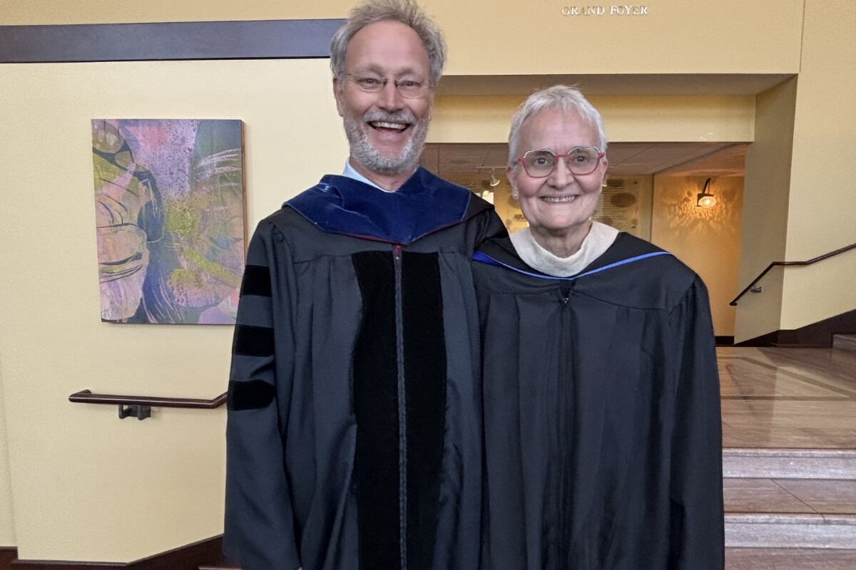 Photo of a smiling man and woman wearing graduation regalie