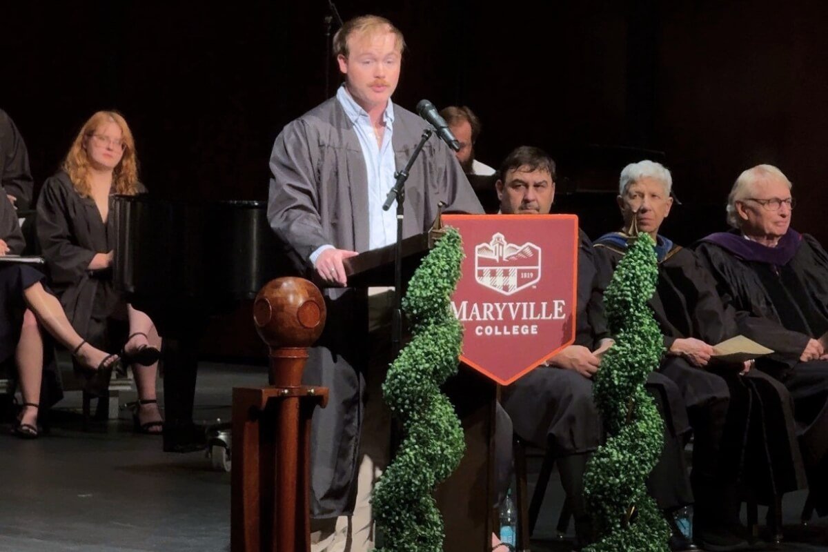 Photo of a college senior standing at a podium and giving an address