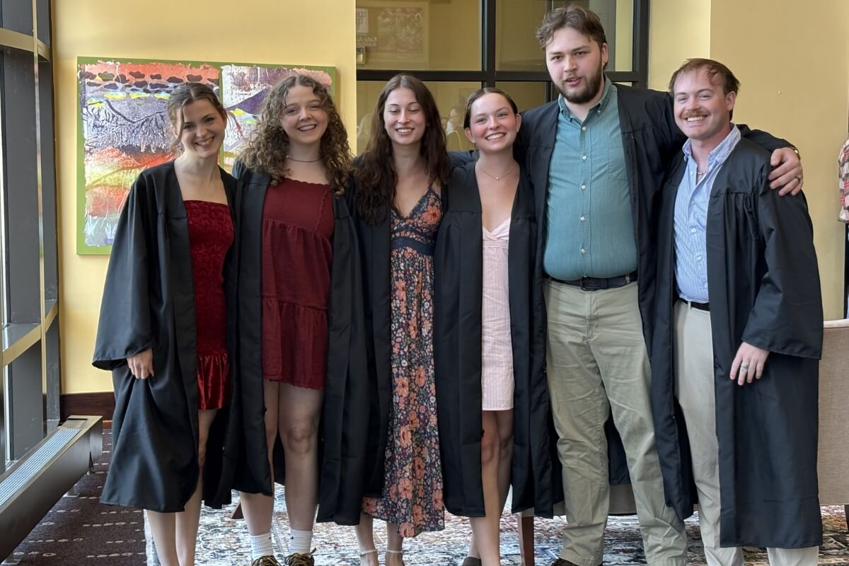 Photo of several soon-to-be college graduates standing in front of a window