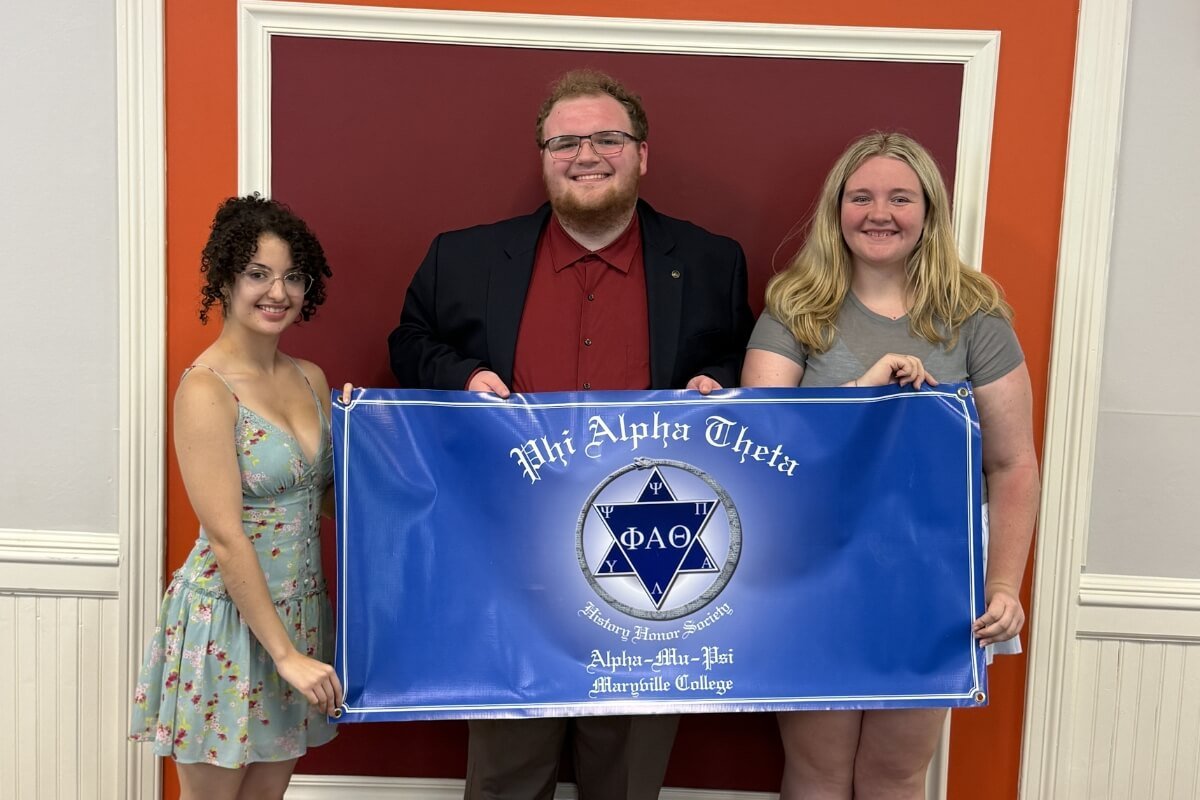 Photo of three people holding the banner of one of the Maryville College honor societies