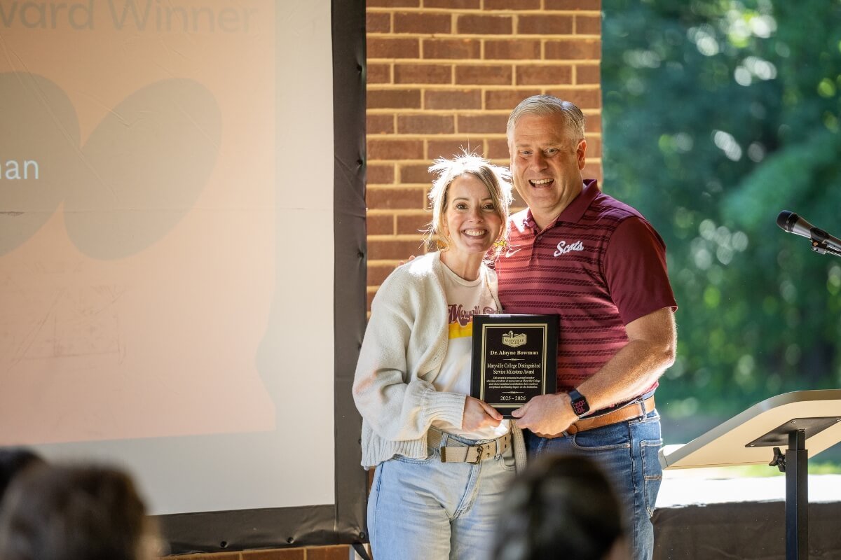 Photo of two people holding a plaque