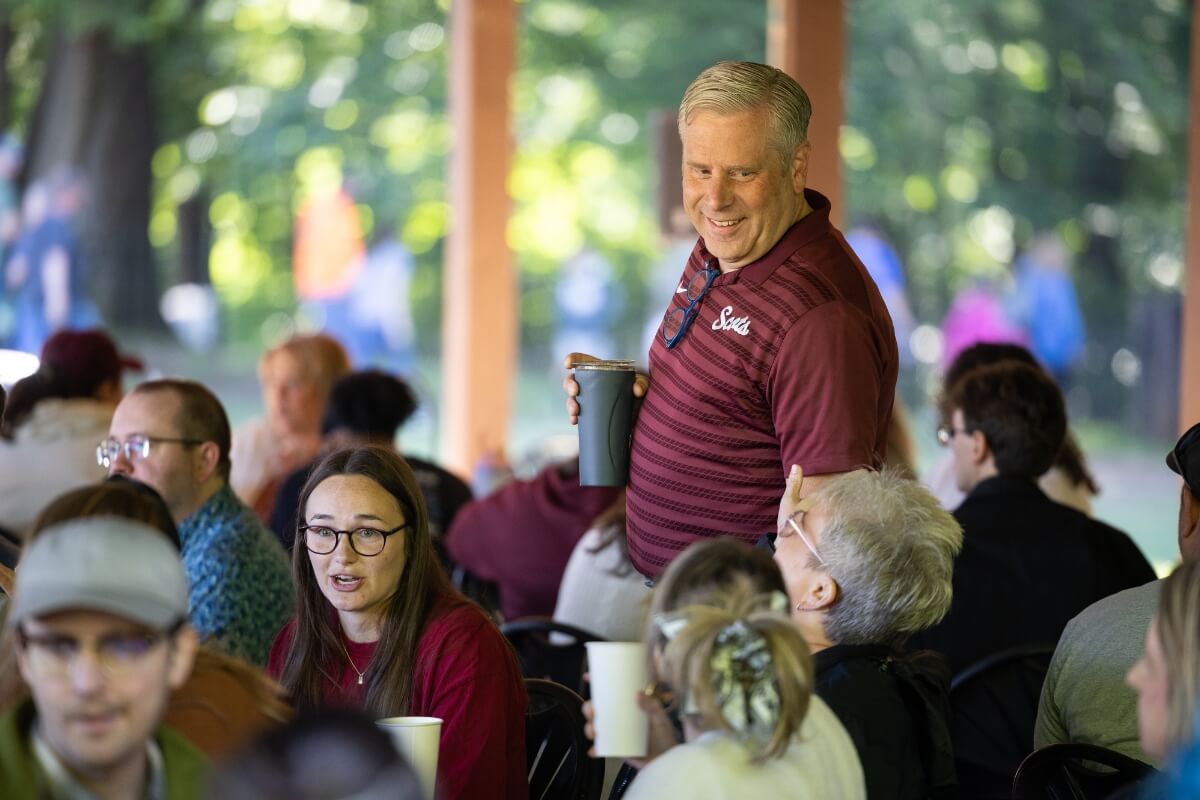 Photo of a man walking through a crowd seated at tables