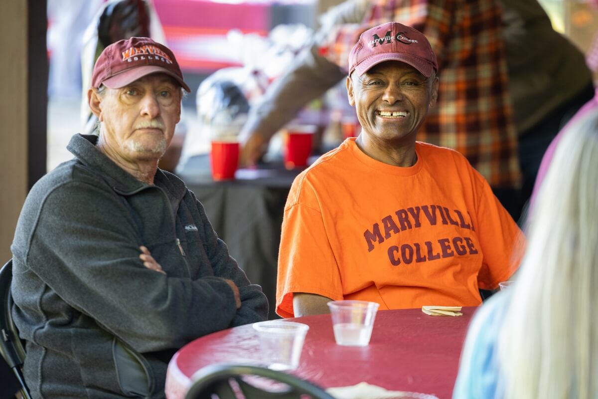 Photo of two men, one smiling and the other scowling